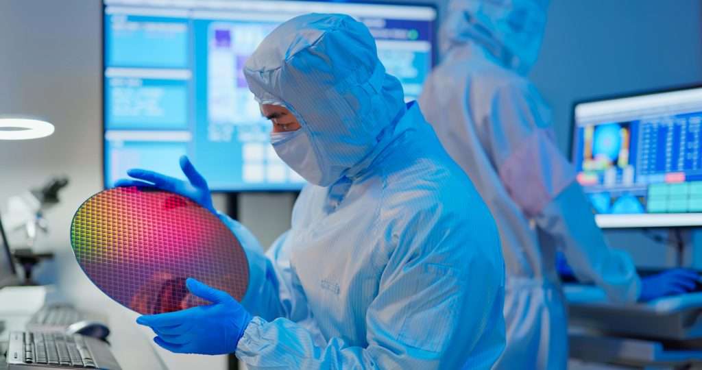 Technician with a silicon wafer in a semiconductor manufacturing plant focused on optoelectronics developments