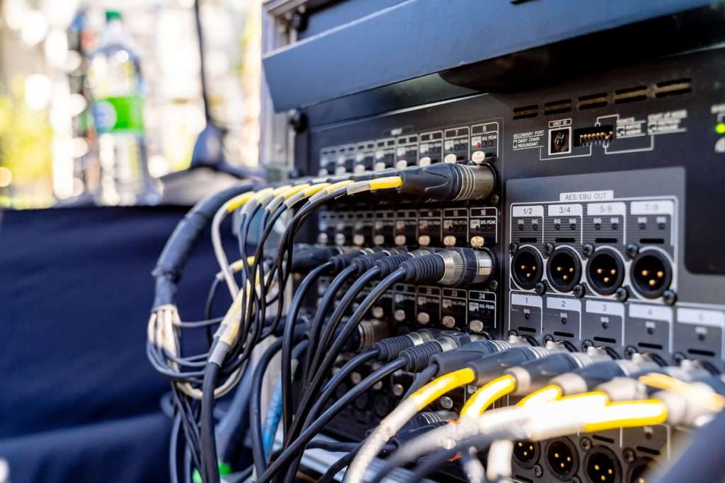 Cables plugged in the inputs of a mixing console and sound amplifier of a sound engineer
