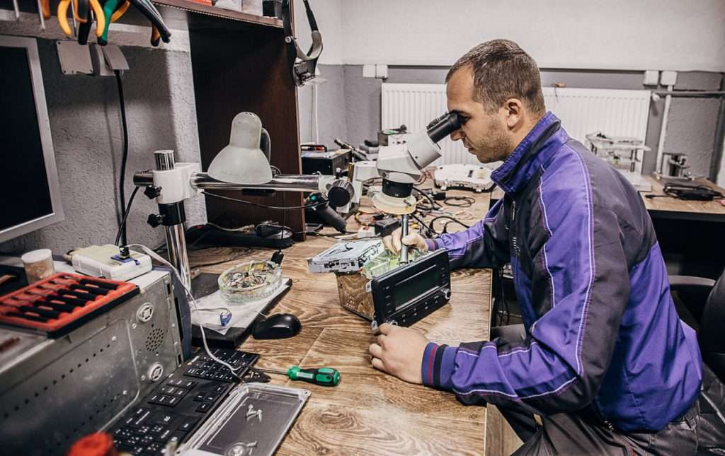 Mechanic replacing amplifier components in a car stereo system in an auto repair shop